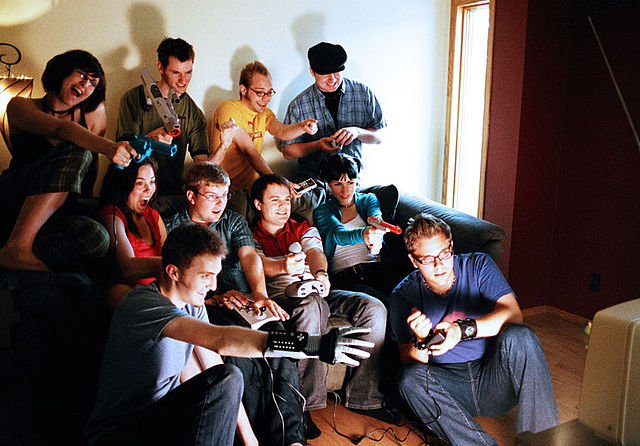 Ten video game players (male and female) in front of a TV set, playing video games